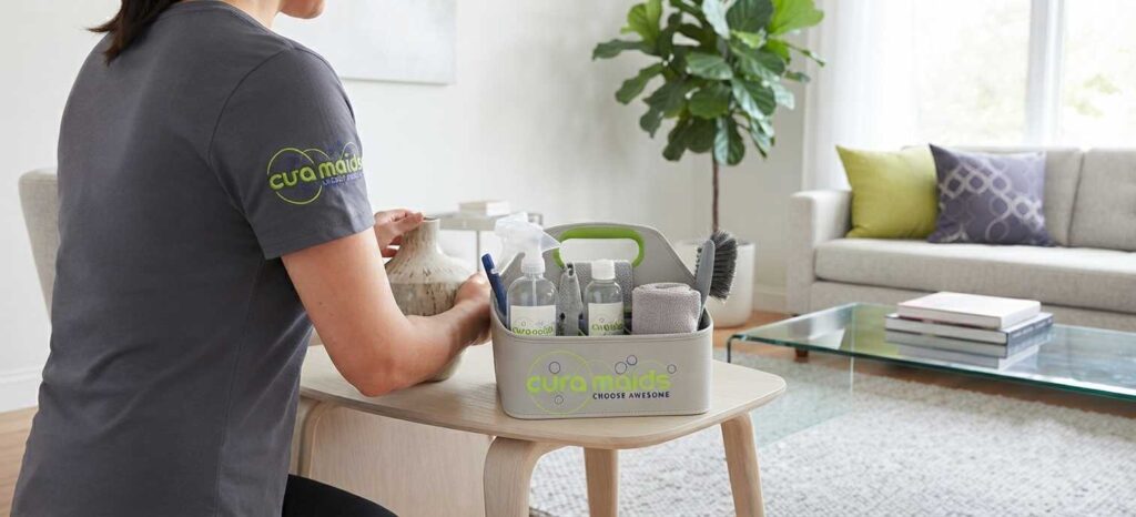 Professional cleaning caddy and tidy living room representing the difference between maid service and cleaning service explained in Cura Maids guide